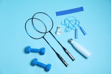 Photo of Different sports equipment and water bottle on light blue background, flat lay