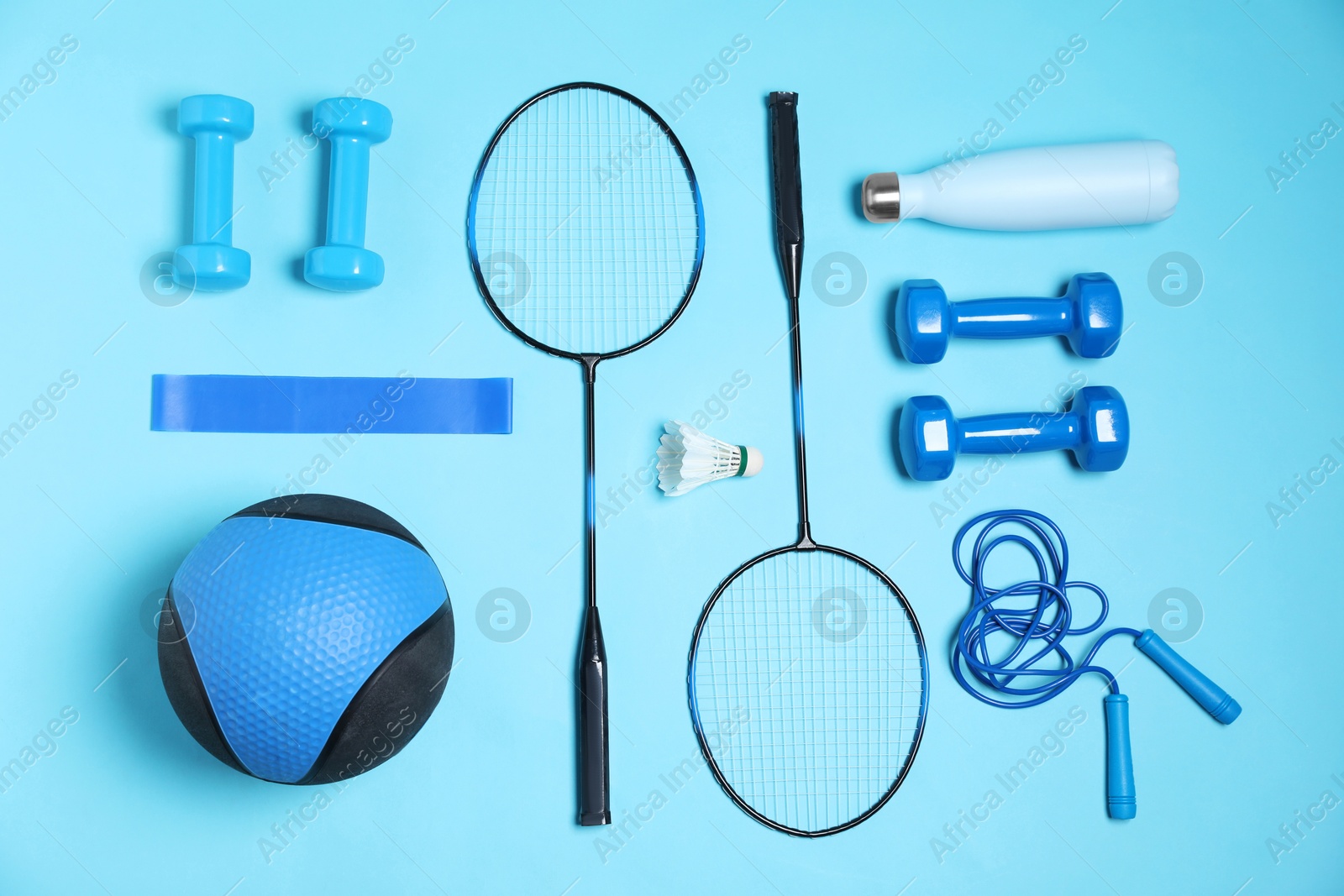 Photo of Different sports equipment and water bottle on light blue background, flat lay