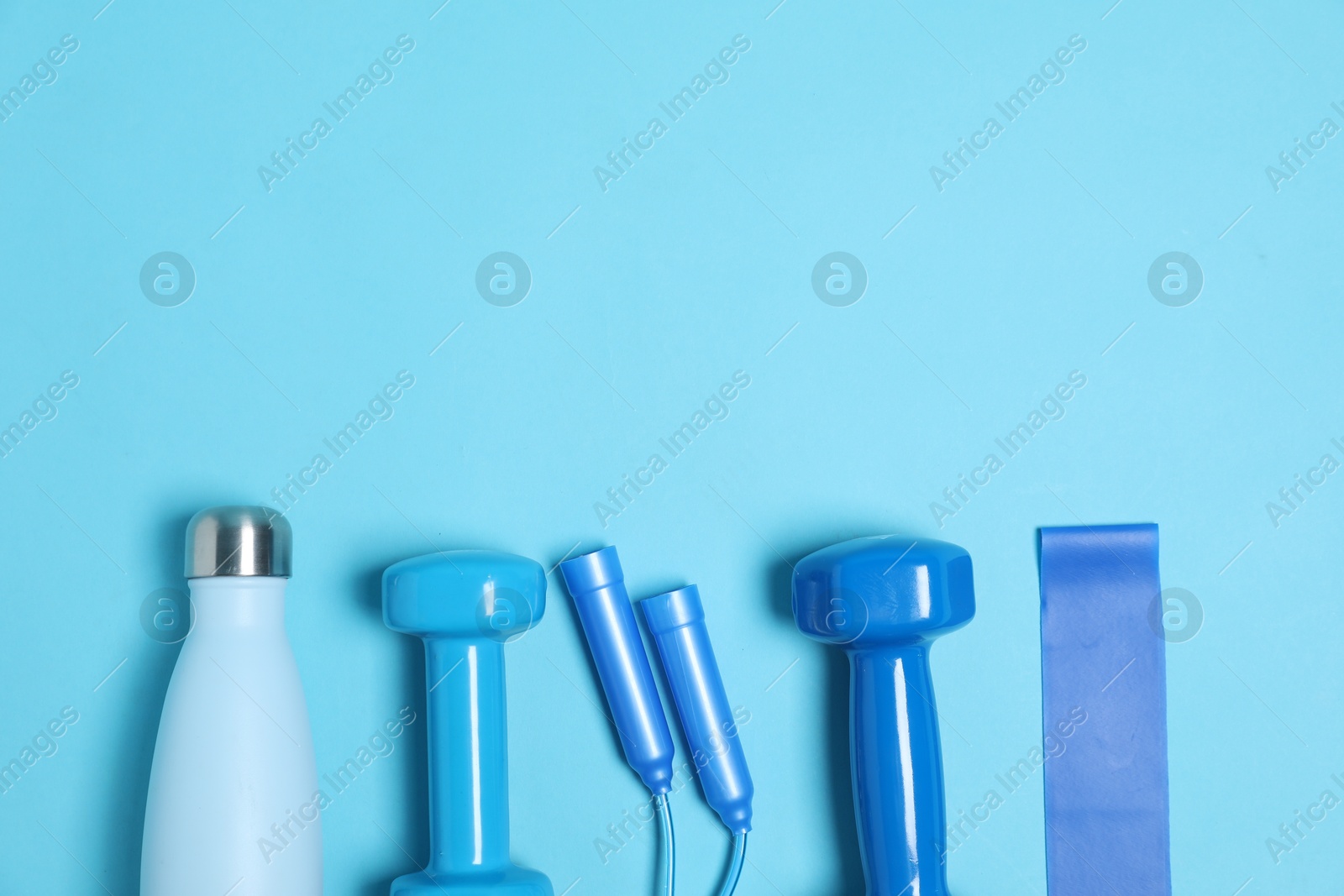 Photo of Different sports equipment and water bottle on light blue background, flat lay. Space for text