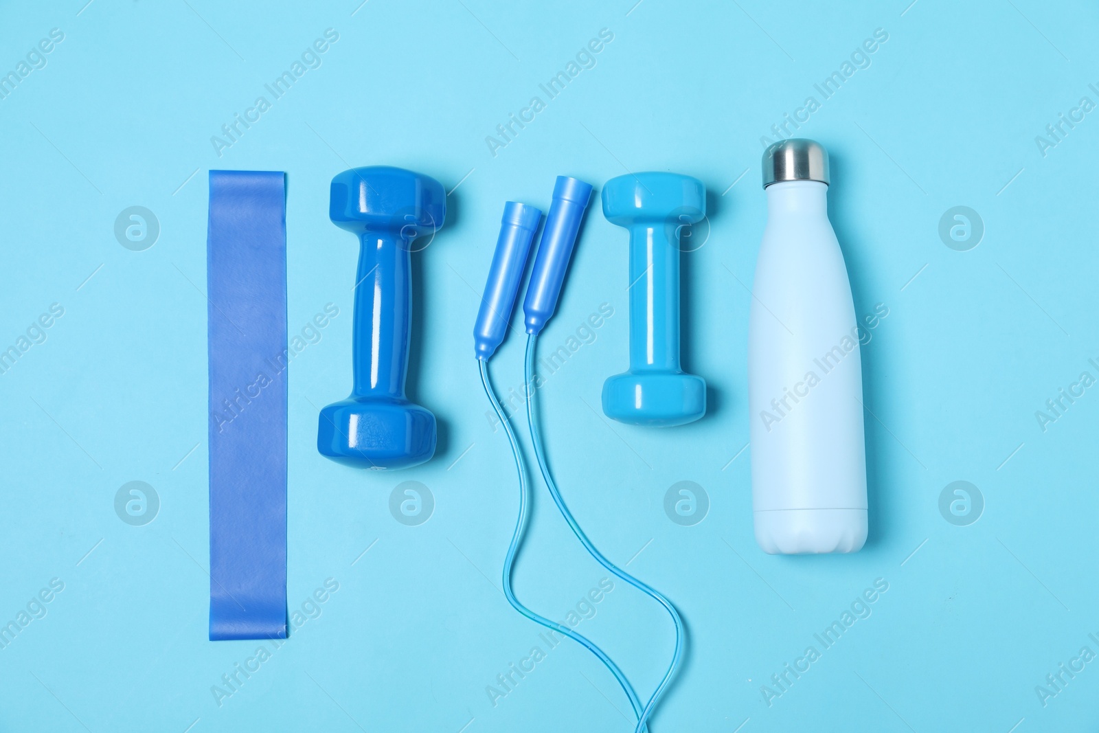 Photo of Different sports equipment and water bottle on light blue background, flat lay