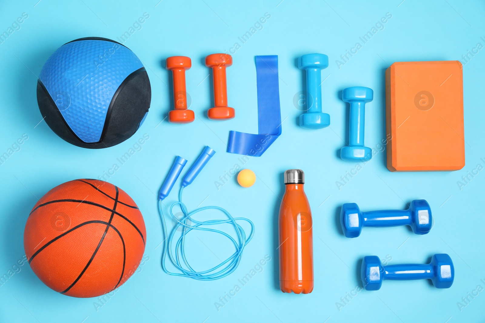 Photo of Different sports equipment and water bottle on light blue background, flat lay