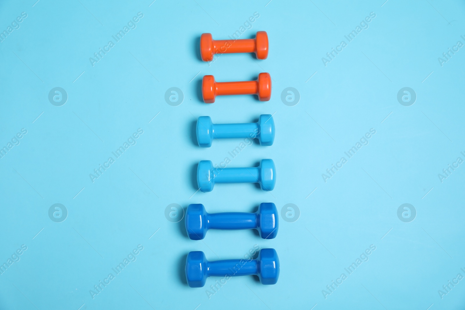 Photo of Different dumbbells on light blue background, flat lay