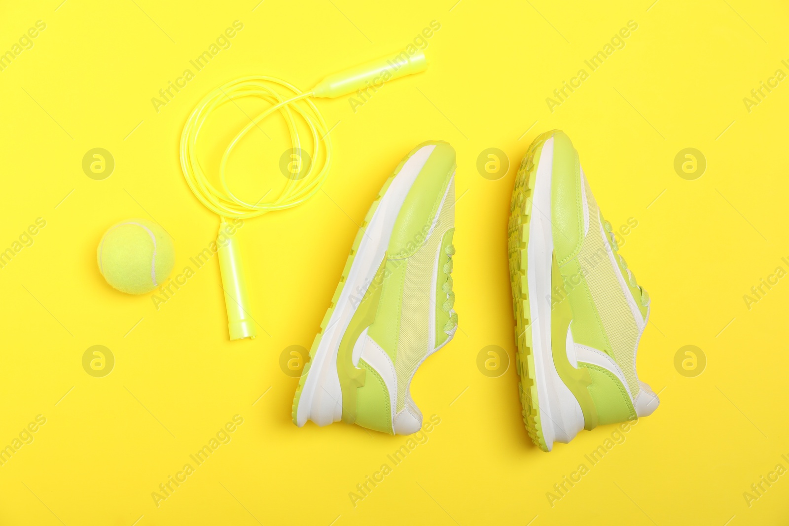 Photo of Different sports equipment and sneakers on yellow background, flat lay