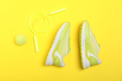 Photo of Different sports equipment and sneakers on yellow background, flat lay