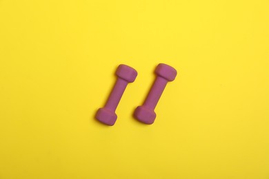 Photo of Dumbbells on yellow background, flat lay. Sports equipment