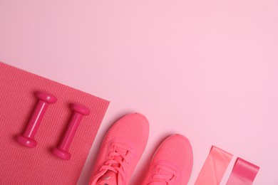 Photo of Sports equipment. Skipping rope, mat, sneakers and dumbbells on pink background, flat lay. Space for text