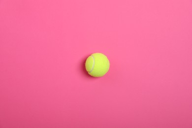 Photo of One tennis ball on bright pink background, top view. Sports equipment