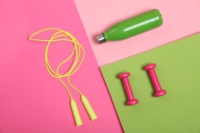 Photo of Different sports equipment and water bottle on pink background, flat lay