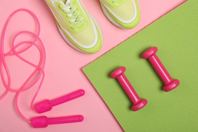 Photo of Different sports equipment and sneakers on pink background, flat lay