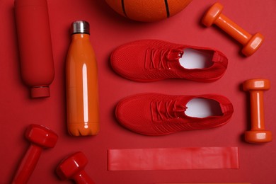 Photo of Different sports equipment and sneakers on red background, flat lay