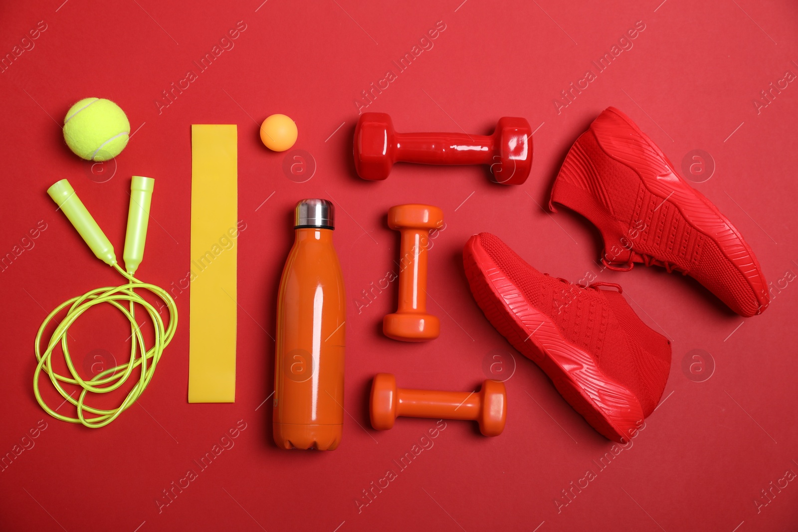 Photo of Different sports equipment and sneakers on red background, flat lay