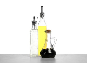 Photo of Oil and vinegars in bottles on table against white background