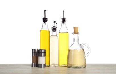 Photo of Salad dressings and spices on wooden table against white background