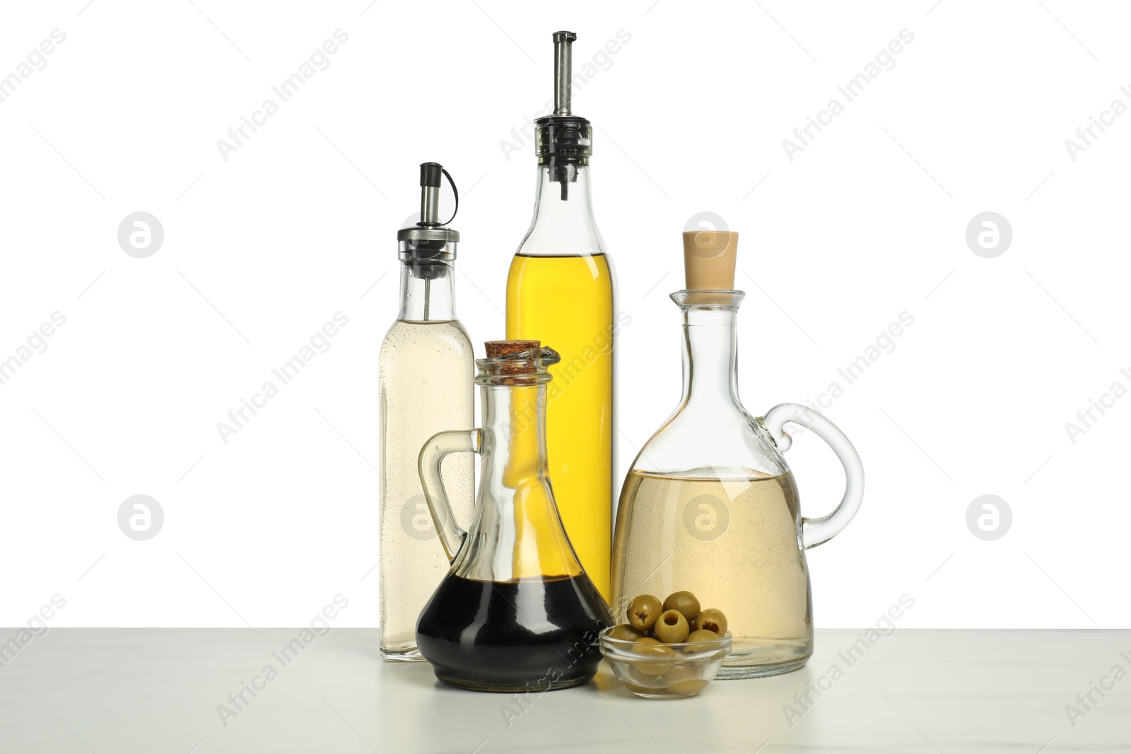 Photo of Salad dressings and olives on table against white background