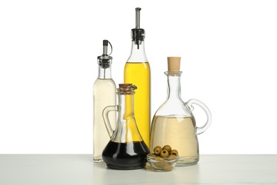 Photo of Salad dressings and olives on table against white background