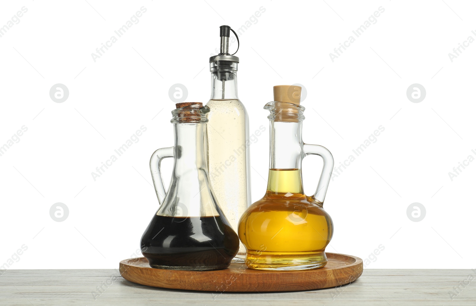 Photo of Oil and vinegars in bottles on wooden table against white background