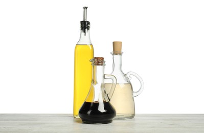 Photo of Oil and vinegars in bottles on wooden table against white background