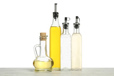 Photo of Oils and vinegars in bottles on wooden table against white background