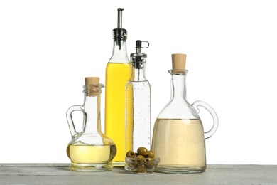 Photo of Salad dressings and olives on grey wooden table against white background