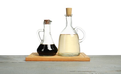 Photo of Vinegars in bottles on grey wooden table against white background