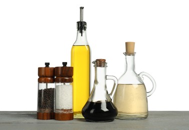 Photo of Salad dressings and spices on grey wooden table against white background