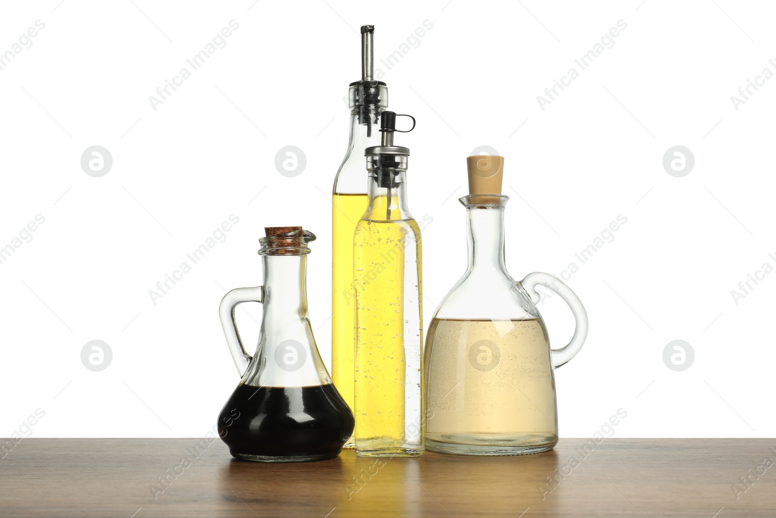 Photo of Oil and vinegars in bottles on wooden table against white background