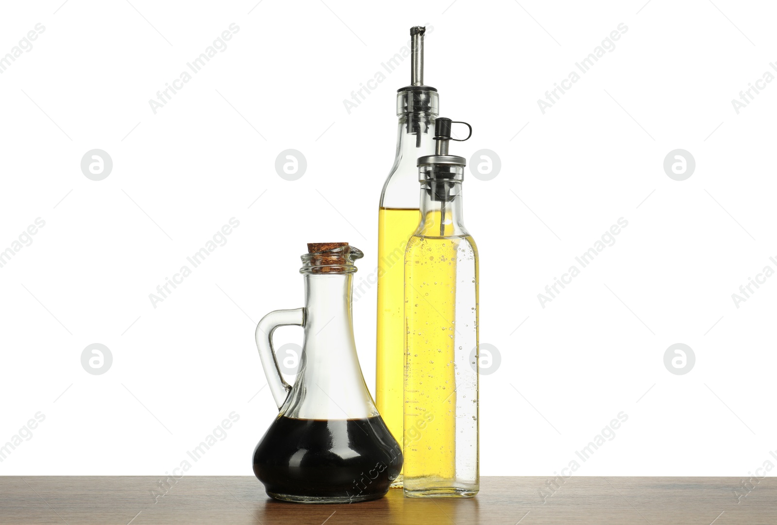 Photo of Oil and vinegars in bottles on wooden table against white background