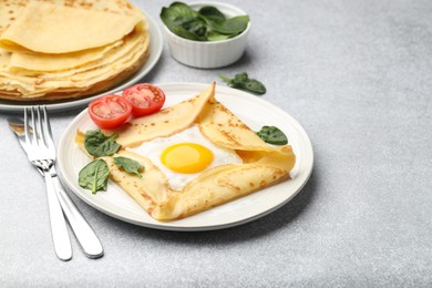 Photo of Delicious crepes with egg, tomato and basil on light grey table, space for text