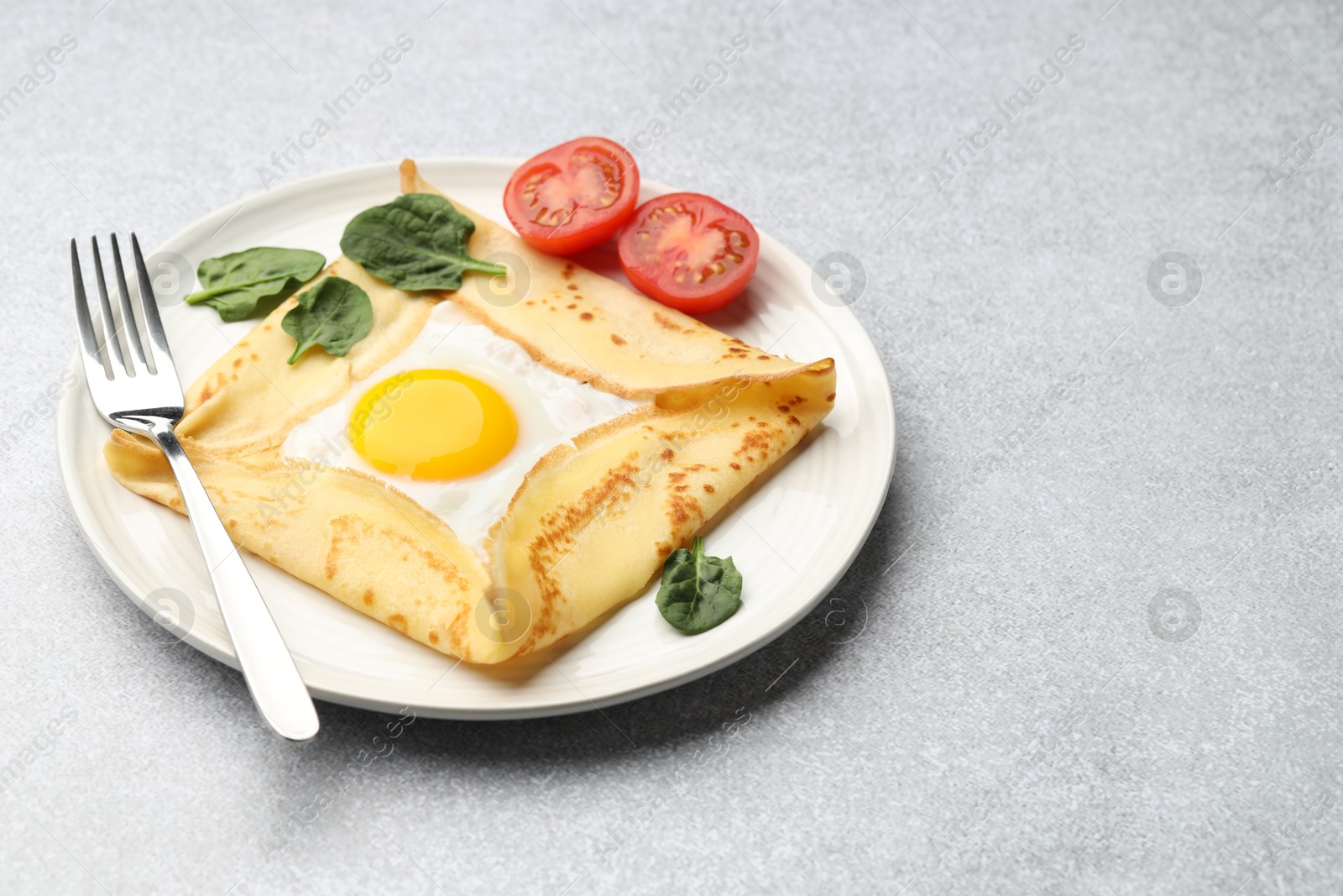 Photo of Delicious crepe with egg, tomato and basil on light grey table, closeup. Space for text