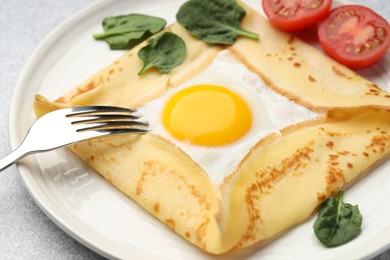 Photo of Delicious crepe with egg, tomato and basil on table, closeup