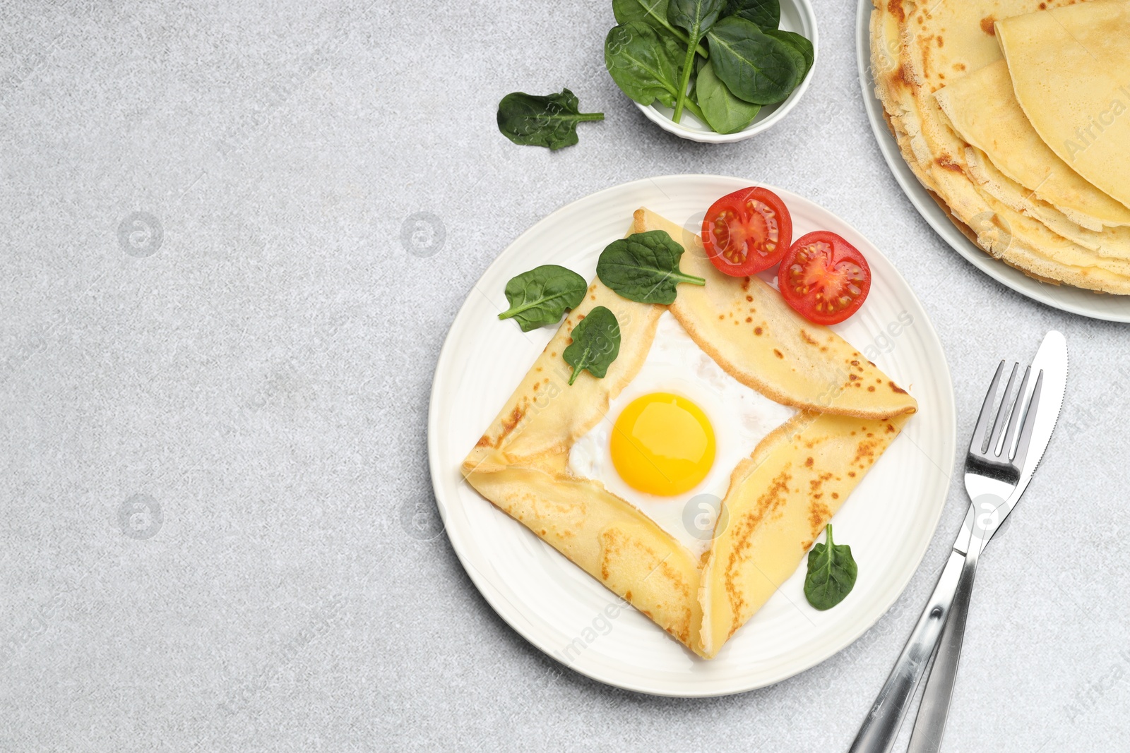 Photo of Delicious crepes with egg, tomato and basil on light grey table, flat lay. Space for text