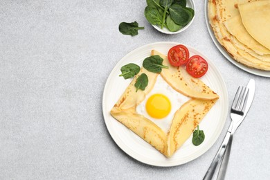 Photo of Delicious crepes with egg, tomato and basil on light grey table, flat lay. Space for text