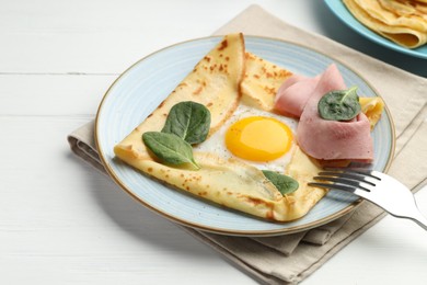 Photo of Delicious crepe with egg, ham and basil on white wooden table, closeup