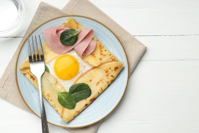 Photo of Delicious crepe with egg, ham, basil and water on white wooden table, flat lay. Space for text