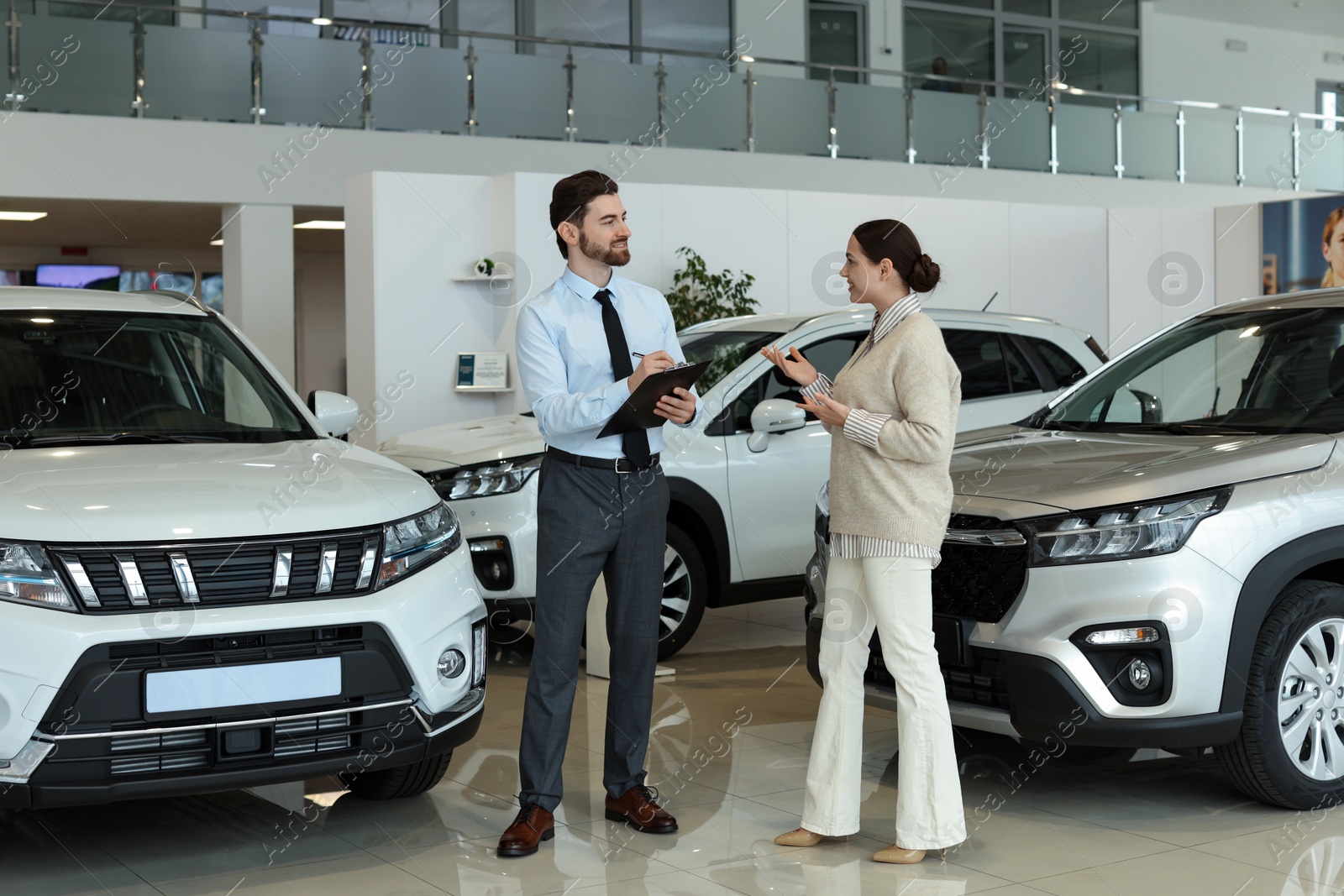 Photo of Happy salesman and client near new car in salon