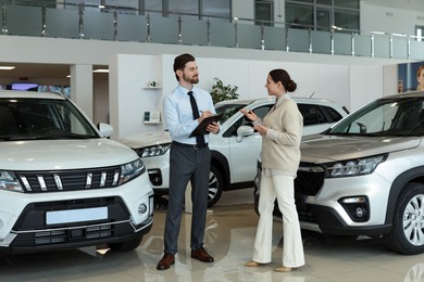 Happy salesman and client near new car in salon