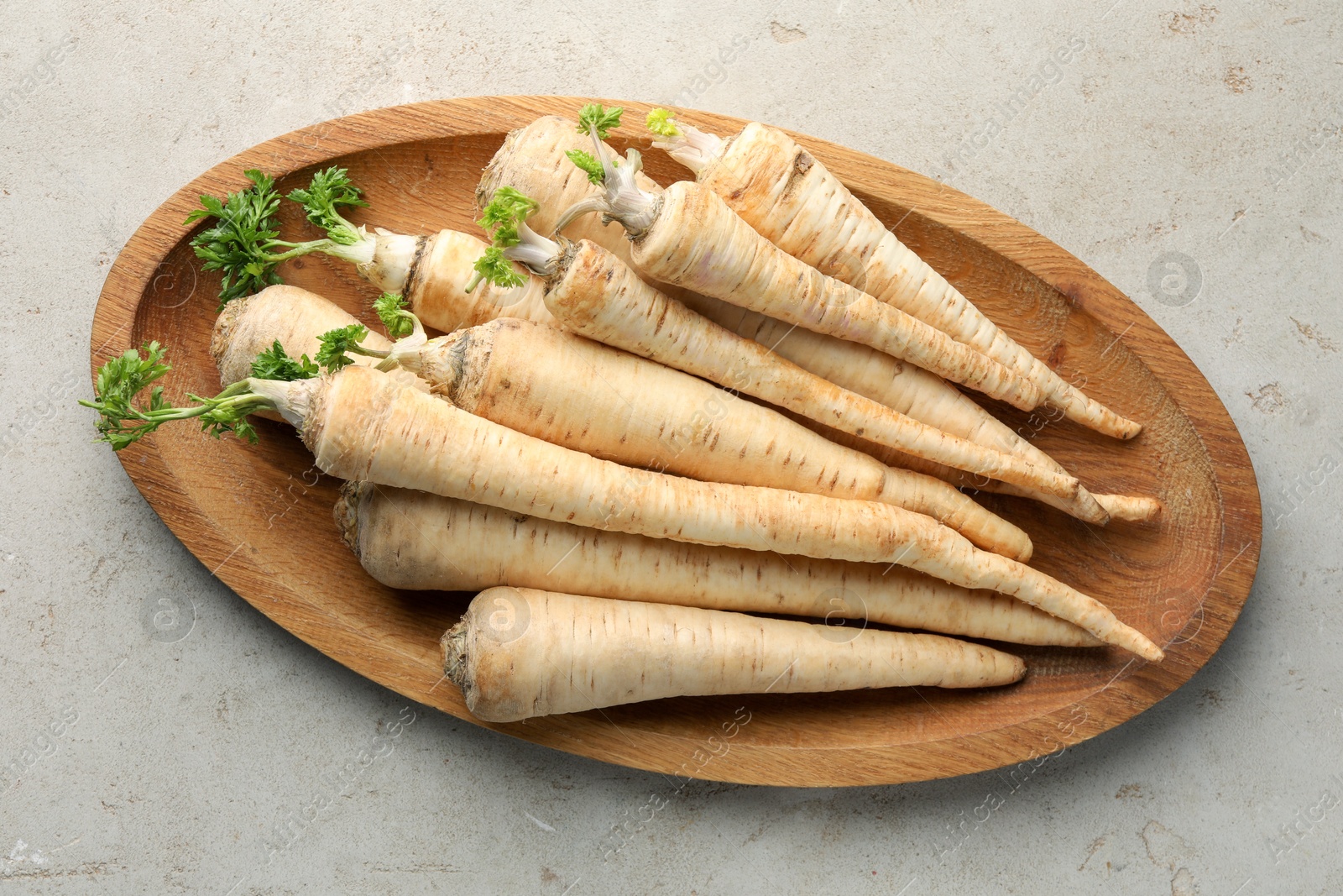 Photo of Many fresh parsley roots on grey table, top view