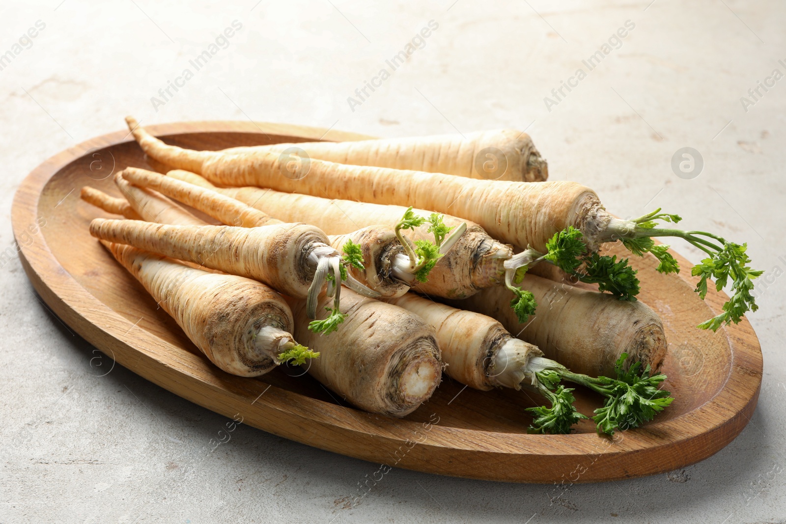 Photo of Many fresh parsley roots on grey table, closeup