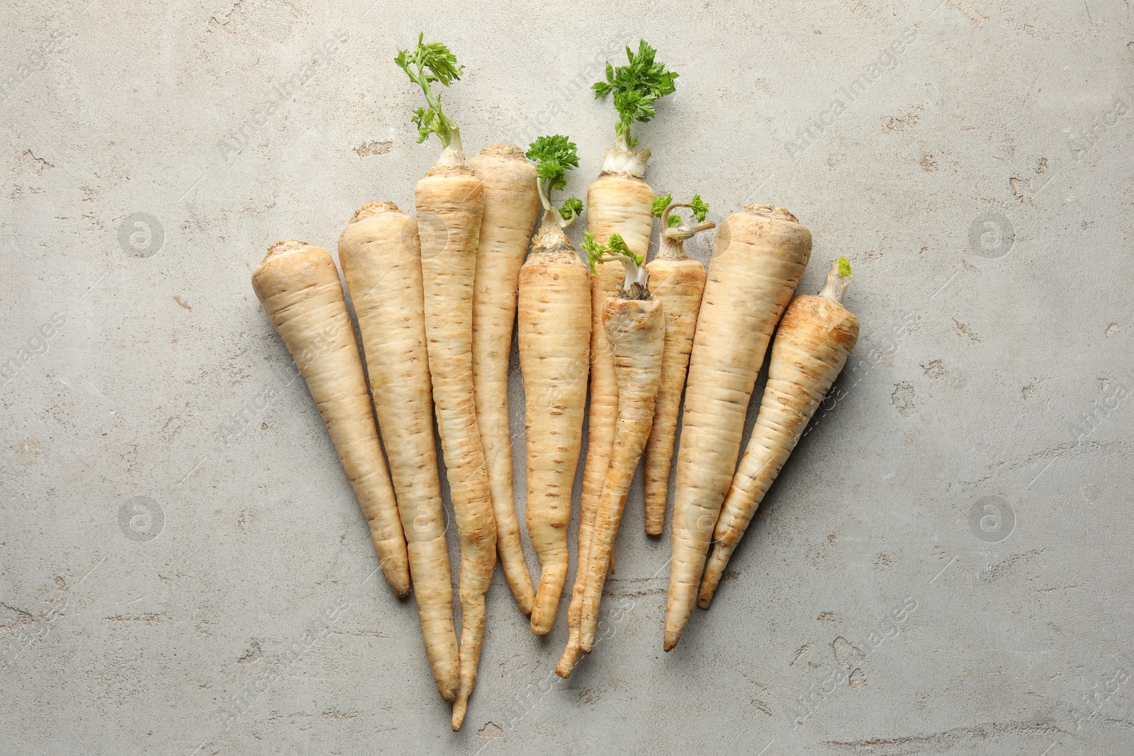 Photo of Many fresh parsley roots on grey table, flat lay