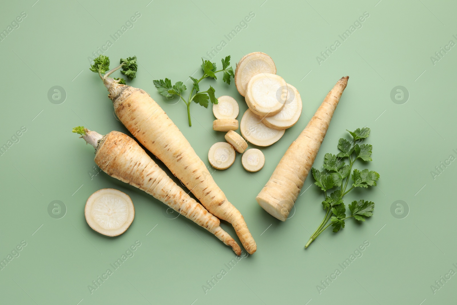 Photo of Parsley roots and leaves on green background, flat lay