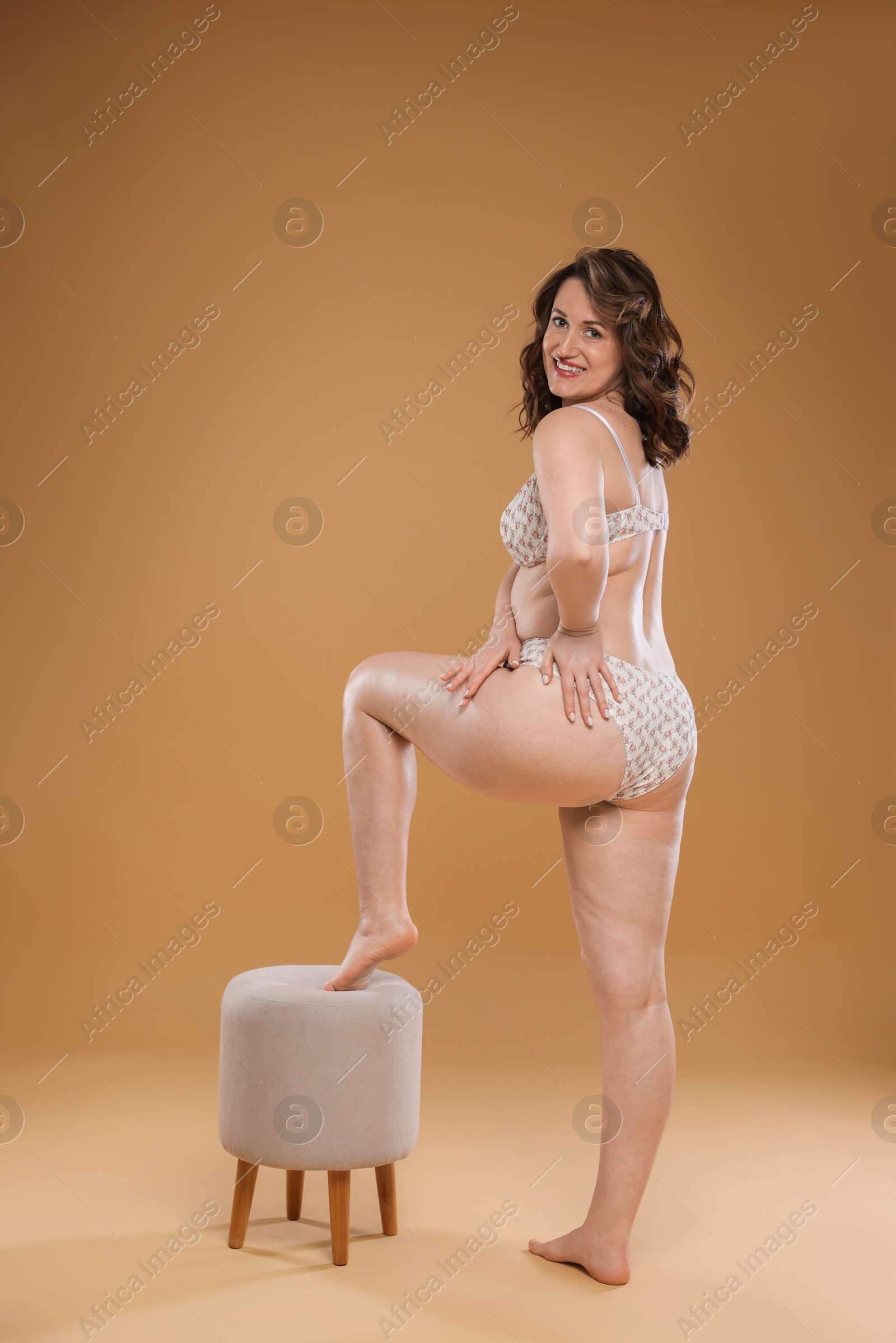 Photo of Beautiful woman in underwear posing on dark beige background. Cellulite problem