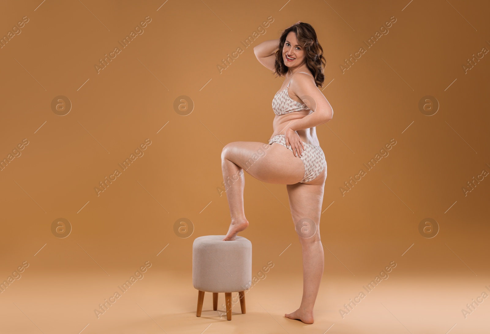 Photo of Beautiful woman in underwear posing on dark beige background. Cellulite problem