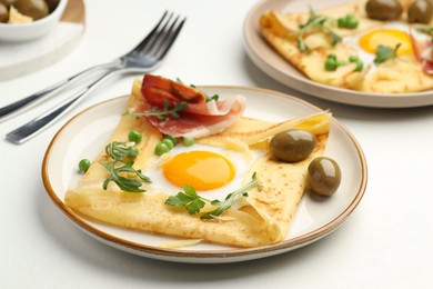 Photo of Delicious crepes with eggs and bacon served on white table, closeup