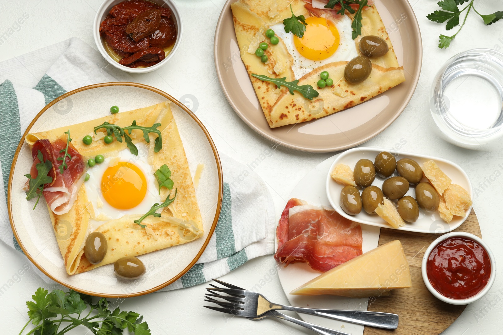 Photo of Delicious crepes with eggs and bacon served on white table, flat lay