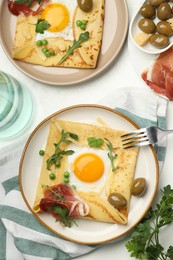 Photo of Delicious crepes with eggs and bacon served on white table, flat lay