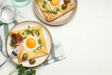 Photo of Delicious crepes with eggs and bacon served on white table, flat lay. Space for text