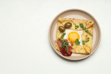 Photo of Delicious crepe with egg, bacon, olives and arugula on white table, top view. Space for text