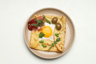 Photo of Delicious crepe with egg, bacon, olives and arugula on white table, top view