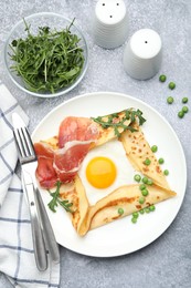 Photo of Delicious crepe with egg, bacon, arugula and green peas on grey table, flat lay