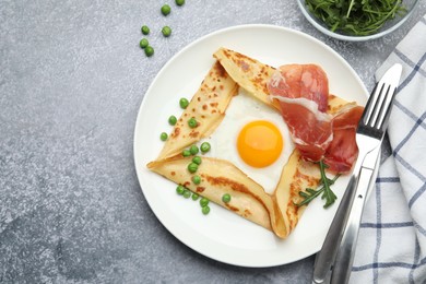 Photo of Delicious crepe with egg, bacon, arugula and green peas on grey table, flat lay. Space for text